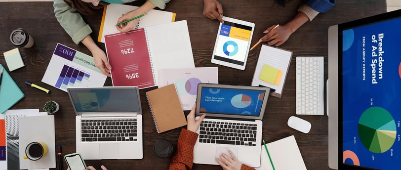 a group of people sitting around a table with laptops