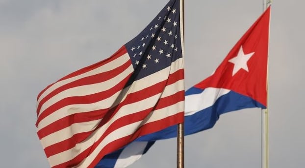 two flags are flying in the sky. USA, Cuba,