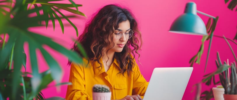 Latina woman smiling while working on a laptop at home, representing side hustle success