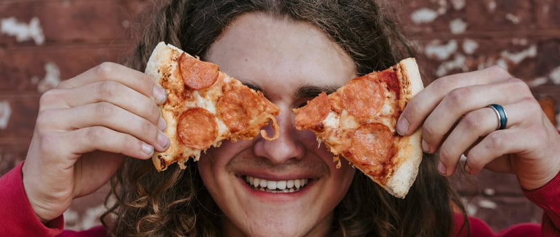 Un adolescent avec des parts de pizza devant ses yeux