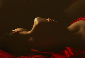 a woman in a red dress laying on a bed