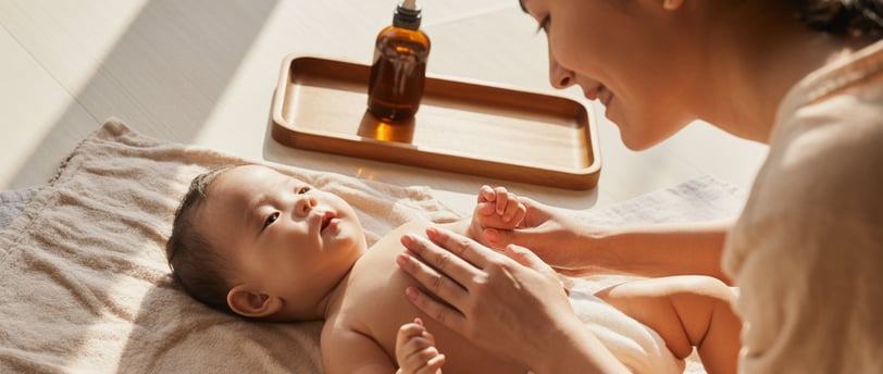 Mẹ châu Á massage nhẹ nhàng cho bé bằng dầu massage cho bé trong không gian ấm áp