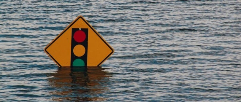 Street sign partially submerged under flood waters.