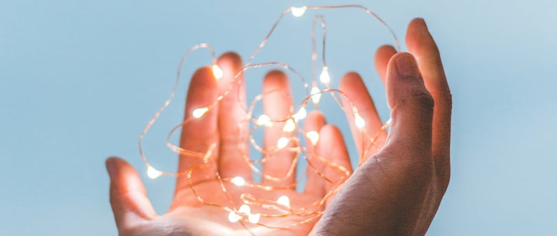a person holding a string light up to the sky
