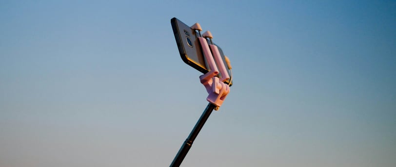 Phone on a selfie stick with blue sky background