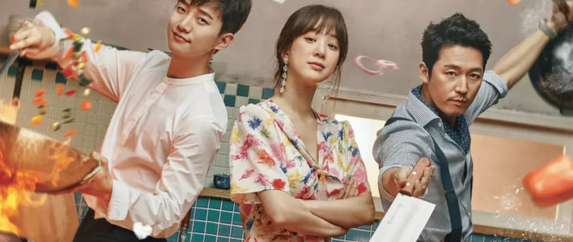 São três Koreanos em uma cozinha com utensílios de cozinha na mão