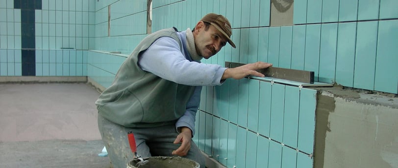 the image displays a guy installing tiles with the help of tile tools