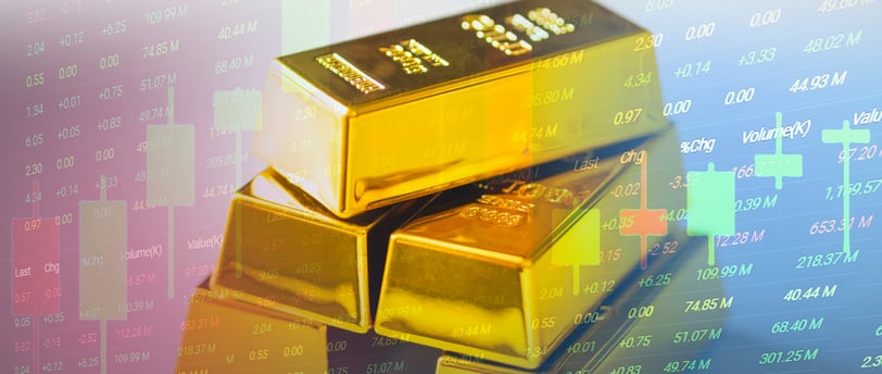 gold bullion bars in a pile with candlesticks and chart data