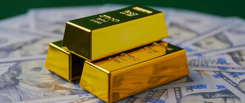gold bars in pyramid on top of 100 dollar bills