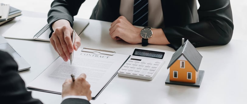 mortgage papers being signed with a calculator on the side for knowing rates