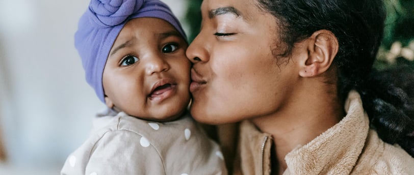 An image of a mother kissing her baby in a secure attachment