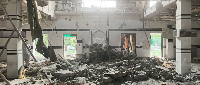 Interior view of a severely damaged building with debris scattered across the floor, b