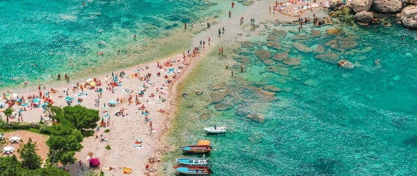 a beach with a boat and people on the water