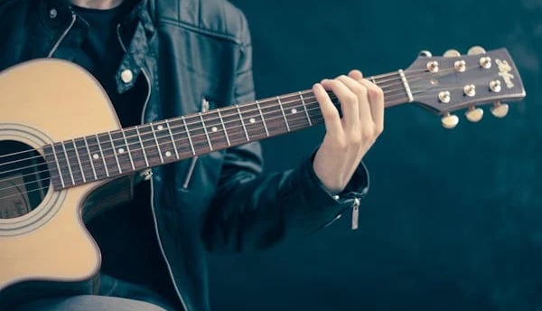 a man in a leather jacket playing guitar