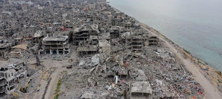 Aerial view of a heavily damaged urban area in Gaza, showing rubble and collapsed buildings, highlig