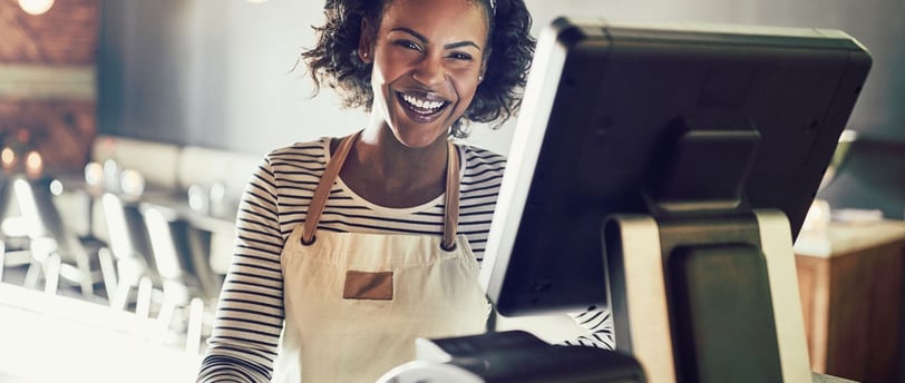 A happy store owner standing behind her point of sale system.