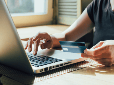 A person using a laptop while holding a credit card, symbolizing online transactions and digital fin