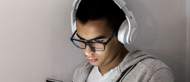 a man in a gray hoodie and headphones on a cell phone