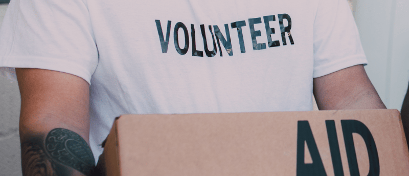 a volunteer in a white shirt is holding a box titled food