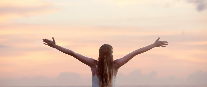 una mujer con brazos abiertos mirando al horizonte