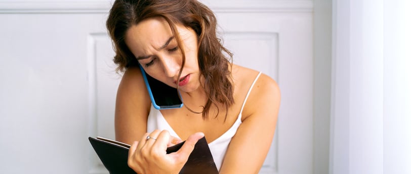 a woman sitting on a bed talking on a cell phone