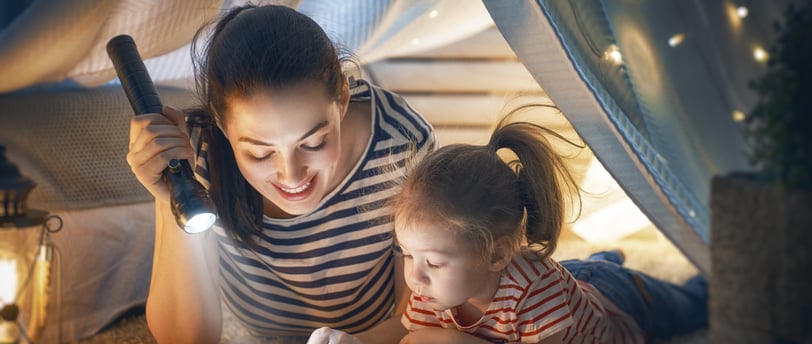 a woman reading a book while her daughter is reading a book