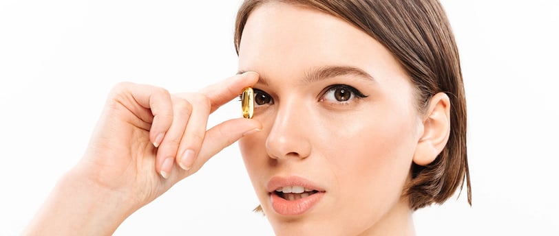 Mujer con una cápsula de omega 3 justo a sus ojos