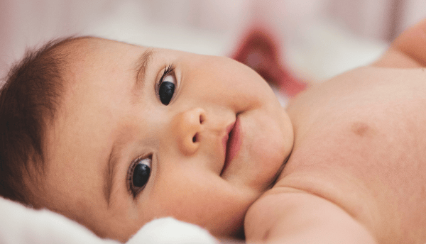 a baby laying and smiling.