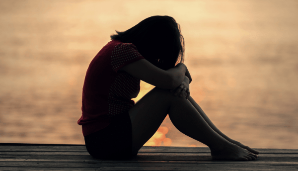 a sad girl sitting on near sea