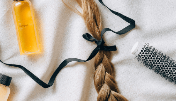 a bottle a brush and a braid of womens hair
