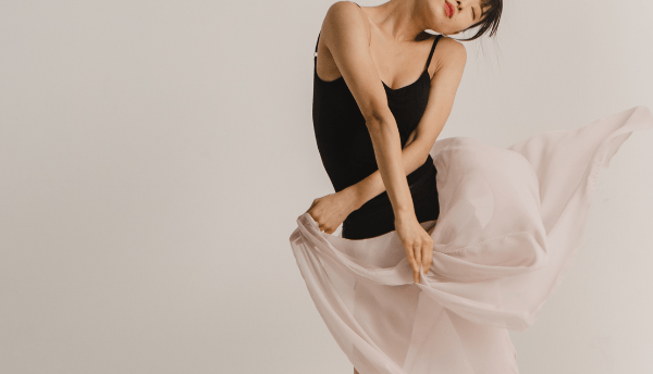 a girl in black top holding pink skirt