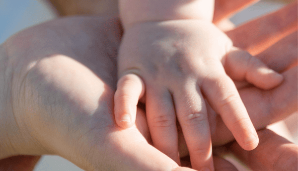 parents holding baby's hand