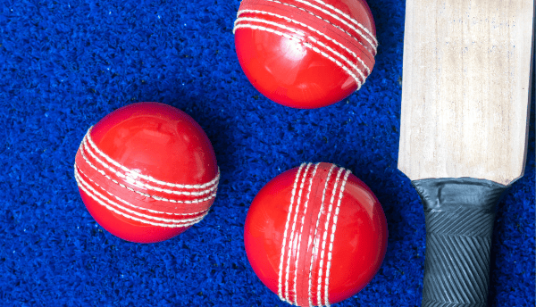 a bat and red colour three balls on blue surface