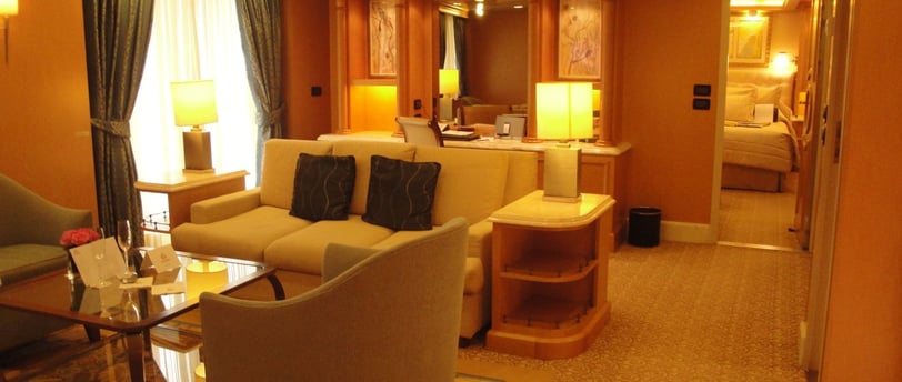 Vista da suíte luxuosa em navio de cruzeiro, com decoração refinada e amplo espaço interno.