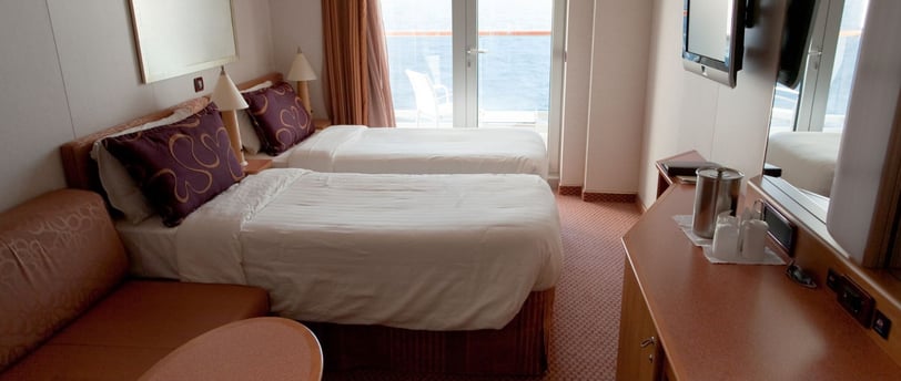 Cabine com duas camas de solteiro em navio de cruzeiro, em layout compacto e bem aproveitado.