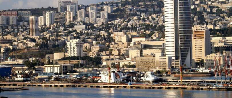 Navio chegando ao Porto de Haifa com vista dos prédios e da cidade ao fundo.