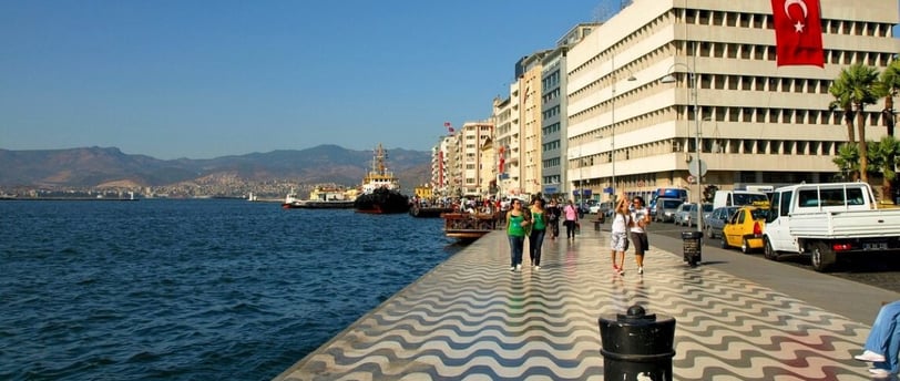 Vista do pier no porto de Izmir, com pessoas indo e vindo, capturando o movimento da cidade.