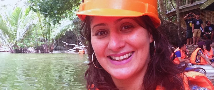 Autora sorrindo ao final do tour pelo Rio Subterrâneo, com vegetação tropical ao fundo.