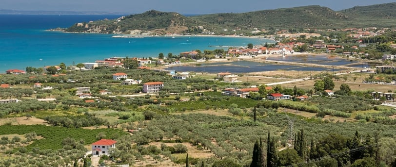 Vista da chegada à praia de Alykes, em Vólos, na Grécia, com o mar calmo ao fundo.