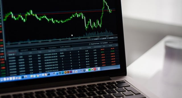 A laptop screen displaying a candlestick chart of a stock.