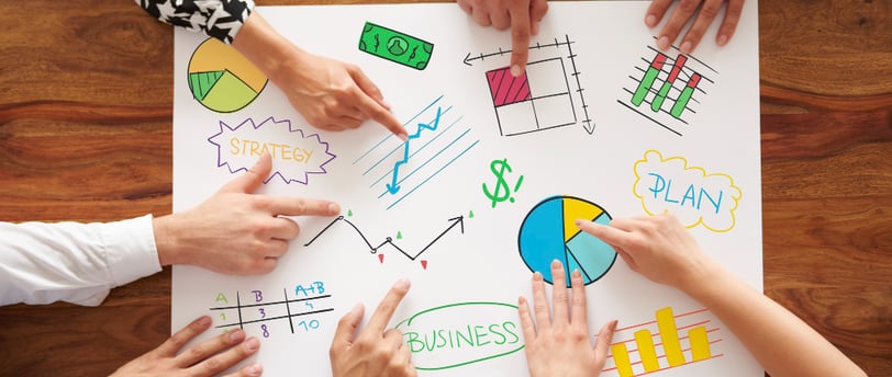 a group of people sitting around a table with a paper board with a diagram of