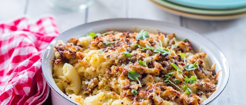 Mac and Cheese in a tin bowl with a crunchy topping and a checked napkin to the side