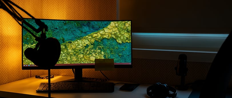 a desk with a computer monitor and a microphone