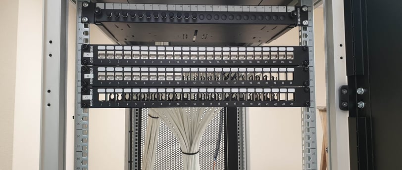 Baie informatique câblée proprement avec panneaux de brassage RJ45 et câbles réseau organisés, installation réalisée par Domi