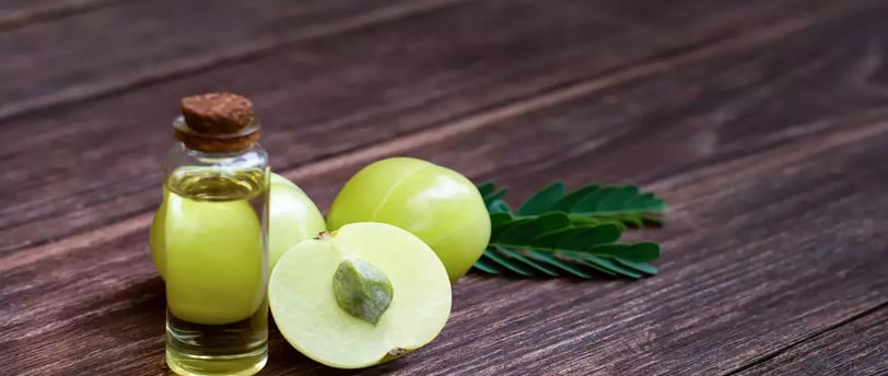 Amla oil bottle with fresh amla fruits, representing natural hair growth and health benefits.
