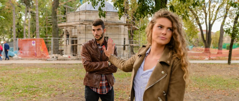 A couple sitting apart, with one partner looking distressed while the other avoids eye contact, symb