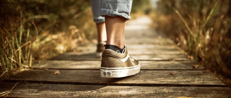 A person walking on a scenic trail, showcasing the physical benefits of walking for weight loss and 