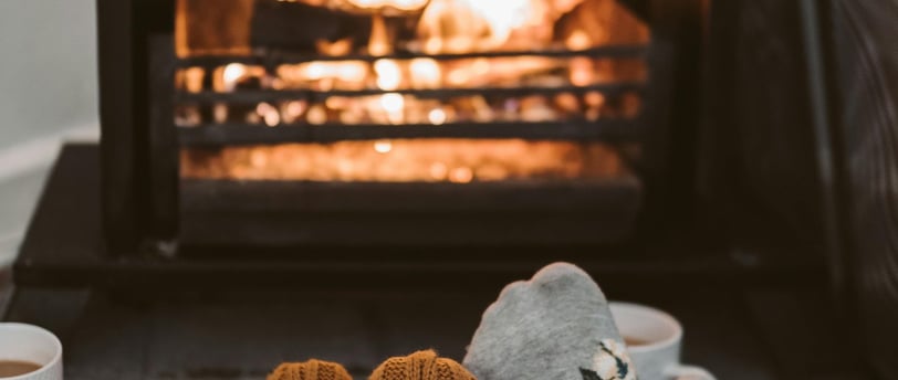 A cozy living room with a warm fireplace, thick blankets, and energy-efficient space heaters,