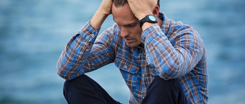 a man sitting on a bench with his hands on his head