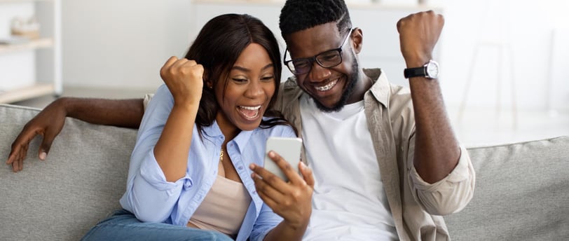 a man and woman sitting on a couch with a cell phone